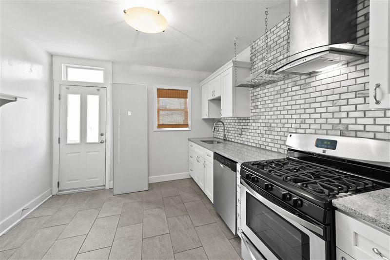Kitchen with a gas range, hood, and tile backsplash