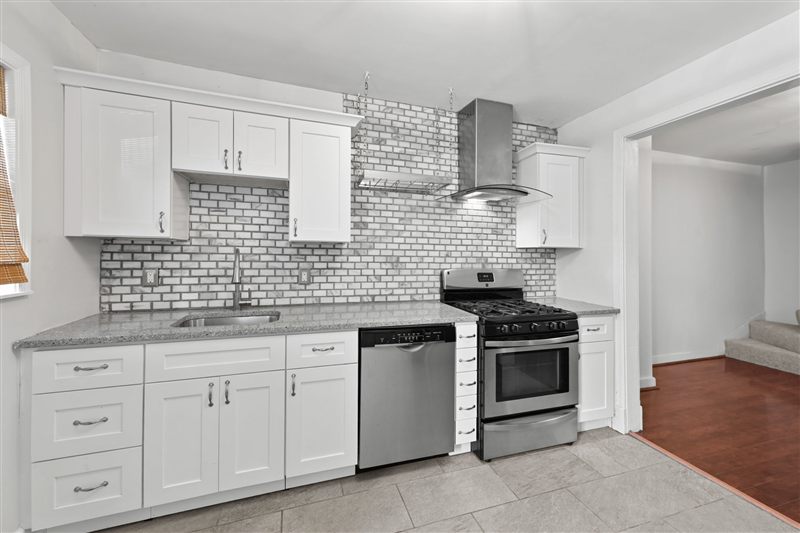 Kitchen with white shaker cabinets, tile backsplash, and stainless appliances