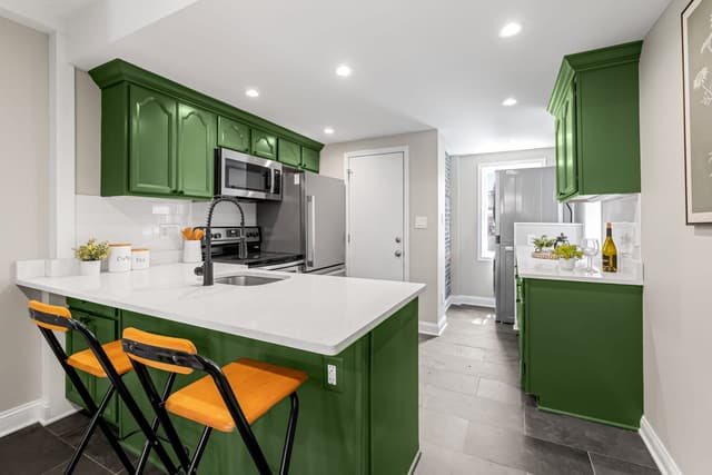 Kitchen peninsula with two stools and green cabinets