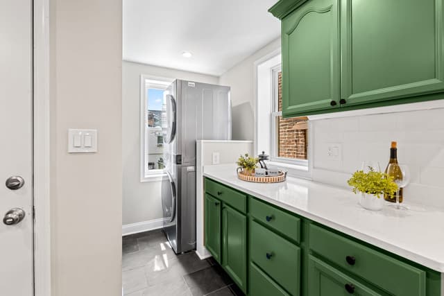 Kitchen counter with green cabinets and a laundry space beside the window