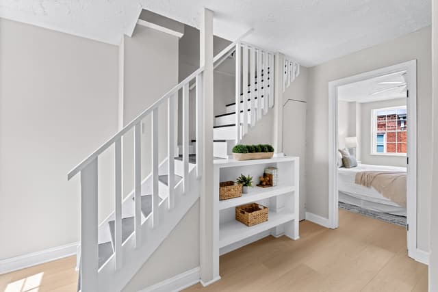 Staircase landing with open shelving and a bedroom door beyond