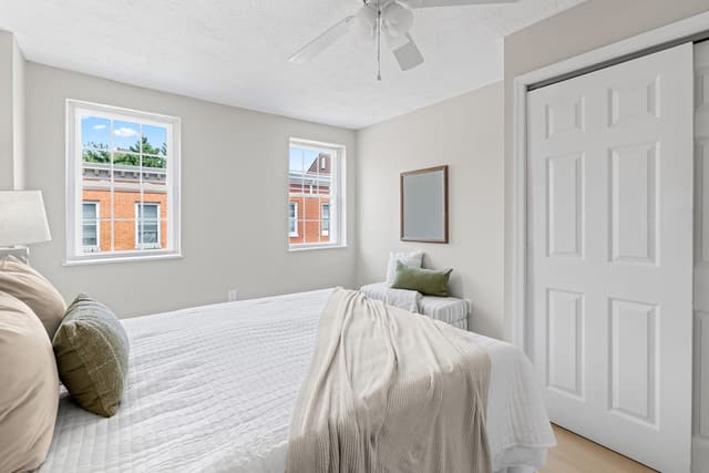 Bedroom windows and a closet with a ceiling fan above