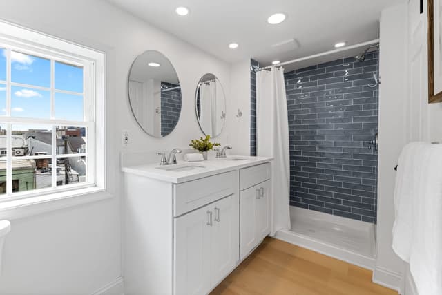 Bathroom with a double vanity and a blue tiled shower
