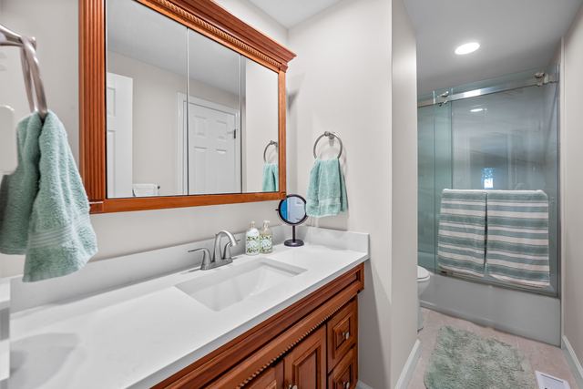Full bath with a long vanity and a glass-door shower