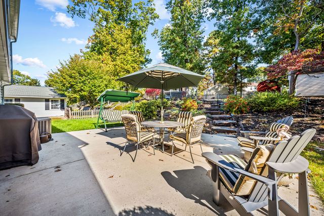 Patio with a dining table, a swing and stone steps up to the yard